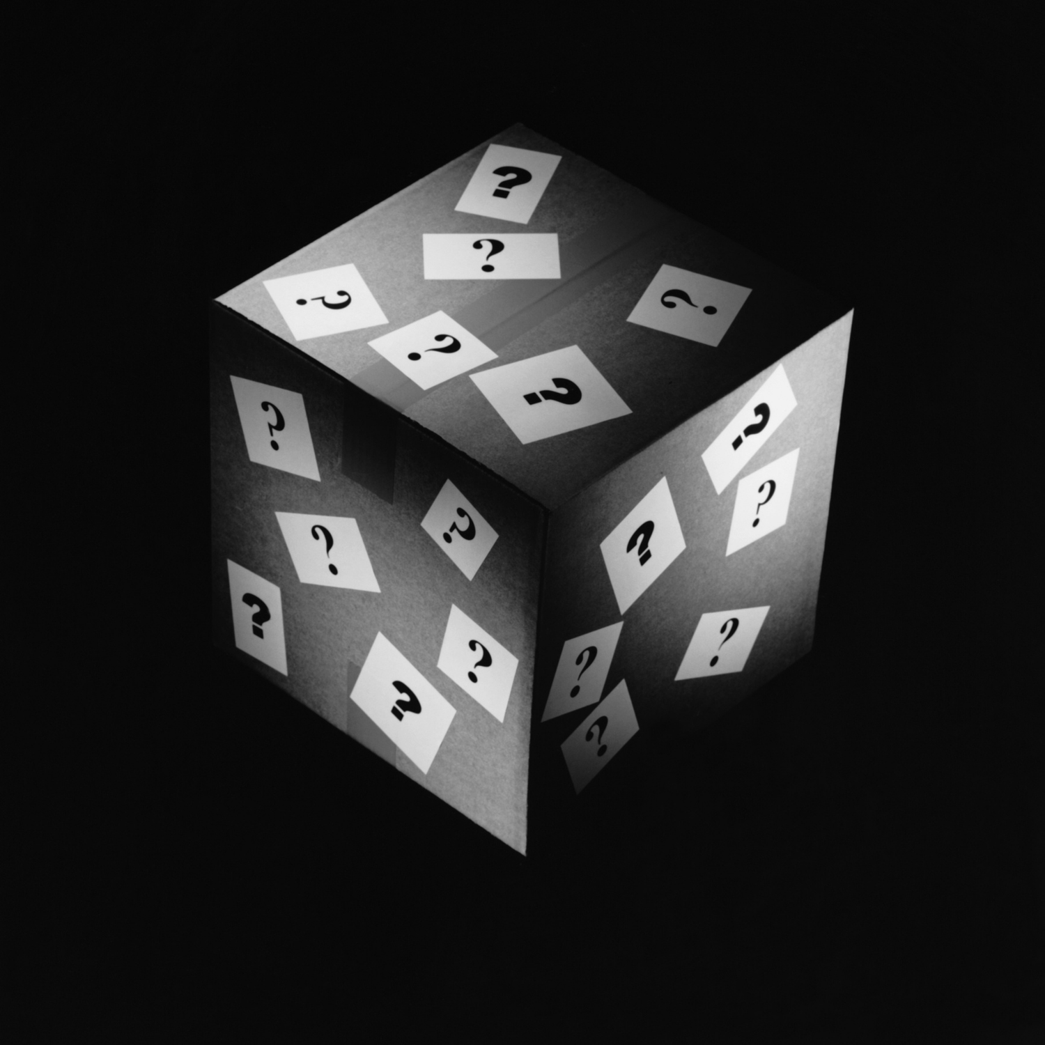 A dark box covered in white cards with black question marks on each face, set against a dark background.